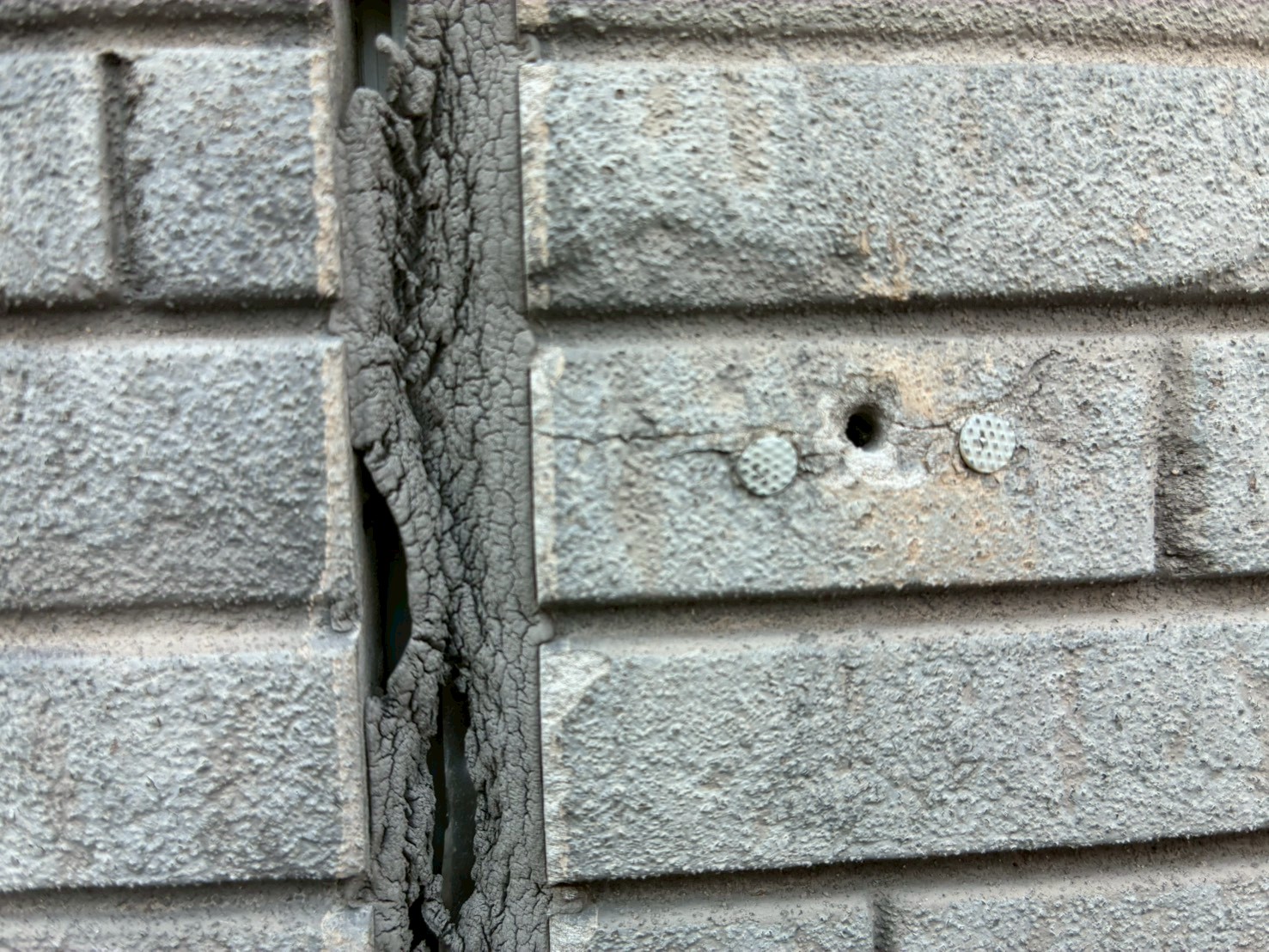 劣化で剥がれたシーリングと外壁の穴